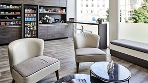 Ein modernes Hotelzimmer mit Sitzgelegenheit, einer Minibar und Blick auf die Stadt.