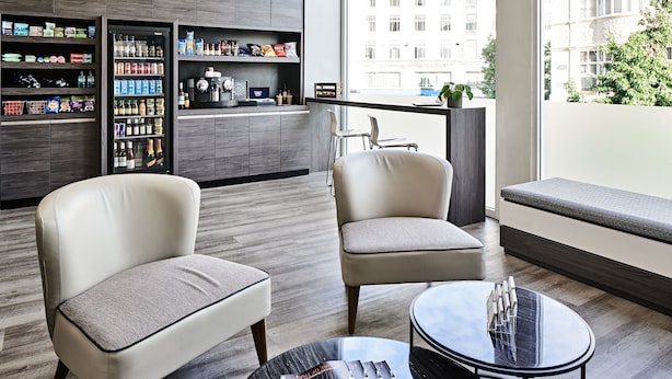 Una habitación de hotel moderna con una zona de estar, minibar y vistas a la ciudad.