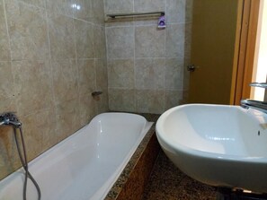 A bathroom with a bathtub, a sink, and a shower. - The Unique Homestay (Ubud)