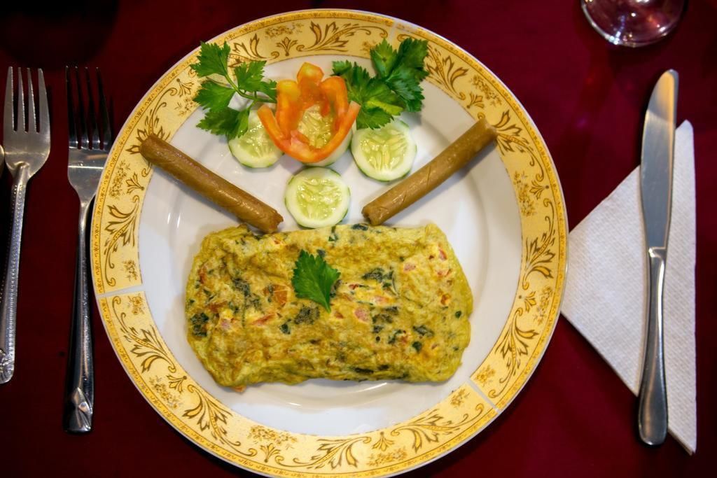 A plate with an omelette, cucumber slices, and a garnish on a decorative plate.