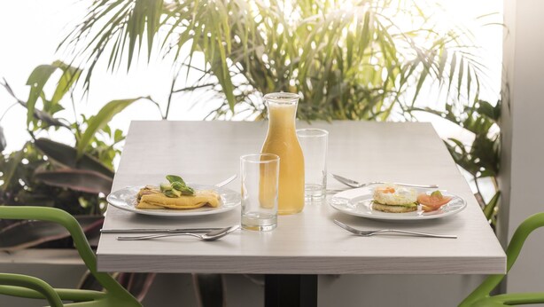 A table set with plates of food, a glass of juice, and a bottle of juice. - Foresta Hotel (Medellín)