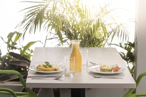 A table set with plates of food, a glass of juice, and a bottle of juice. - Foresta Hotel (Medellín)
