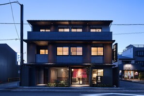 A modern two-story building with a large entrance and a sign indicating a parking area. - Stay SAKURA Kyoto Higashi Hongan-ji I (Kyoto)