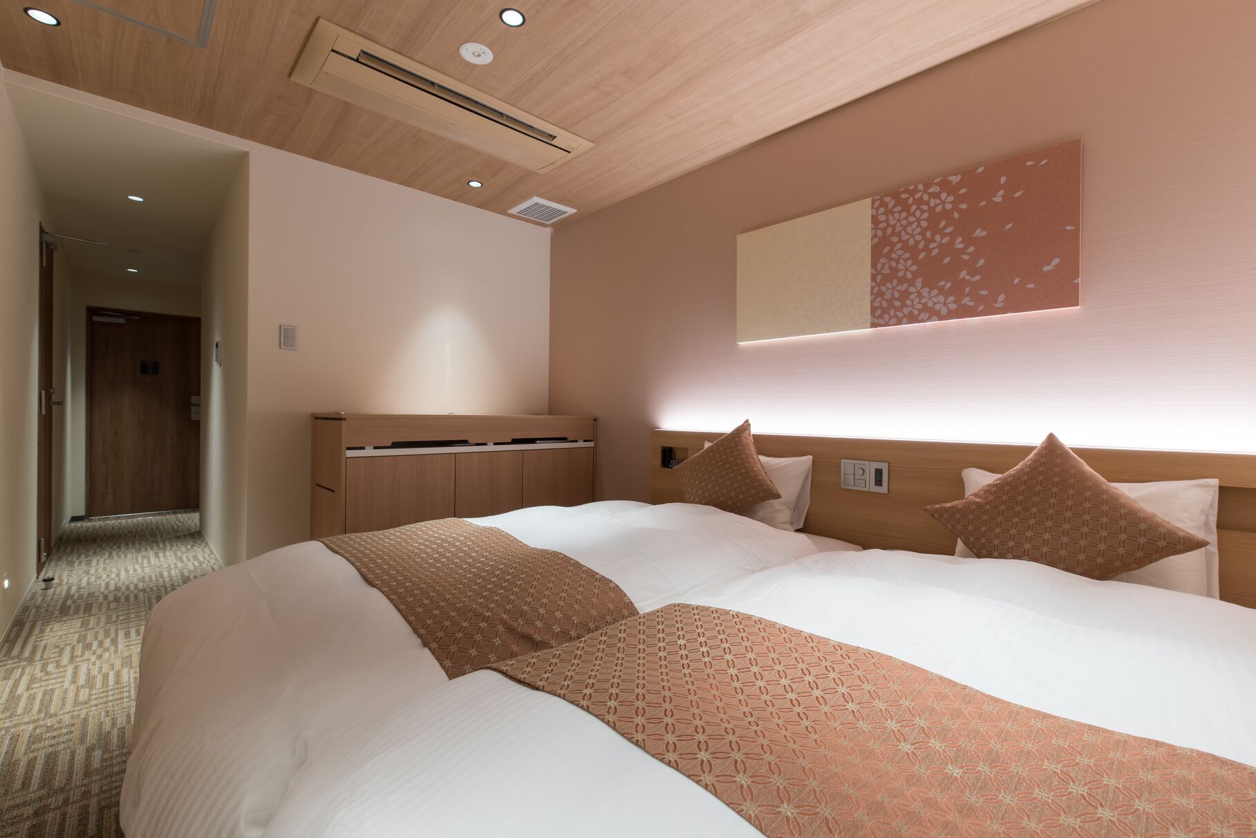A hotel room with a large bed, a wooden headboard, a built-in desk, and a mirror on the wall.