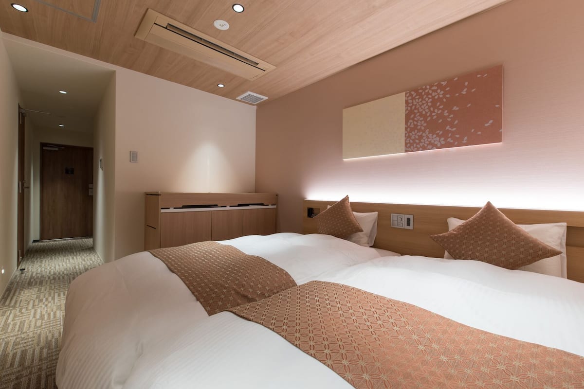Ein Hotelzimmer mit einem großen Bett, einem Holzkopfende, einem fest eingebauten Schreibtisch und einem Spiegel an der Wand.
