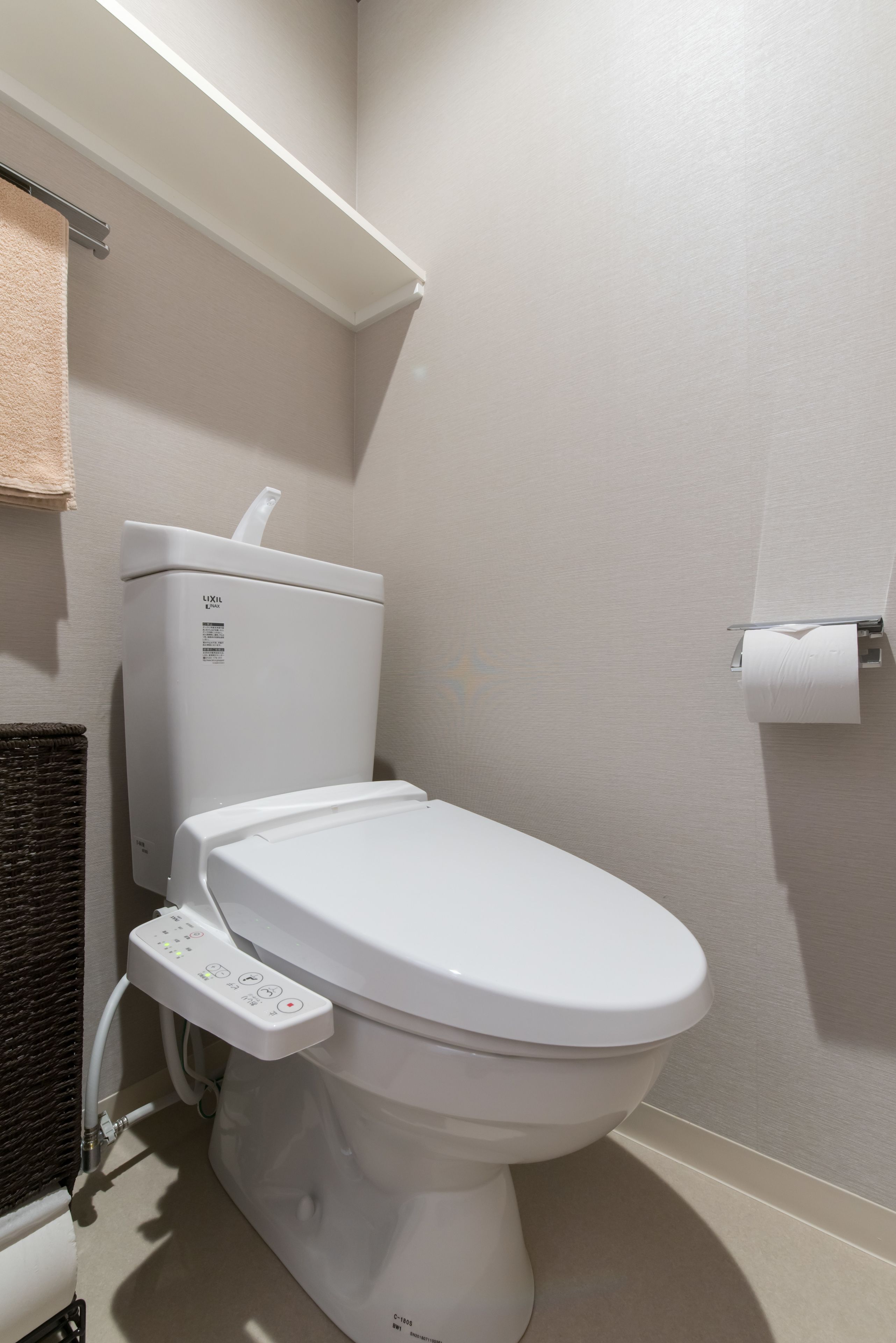 Eine moderne Toilette mit Bedienfeld, Toilettenpapierhalter und Handtuchhalter.