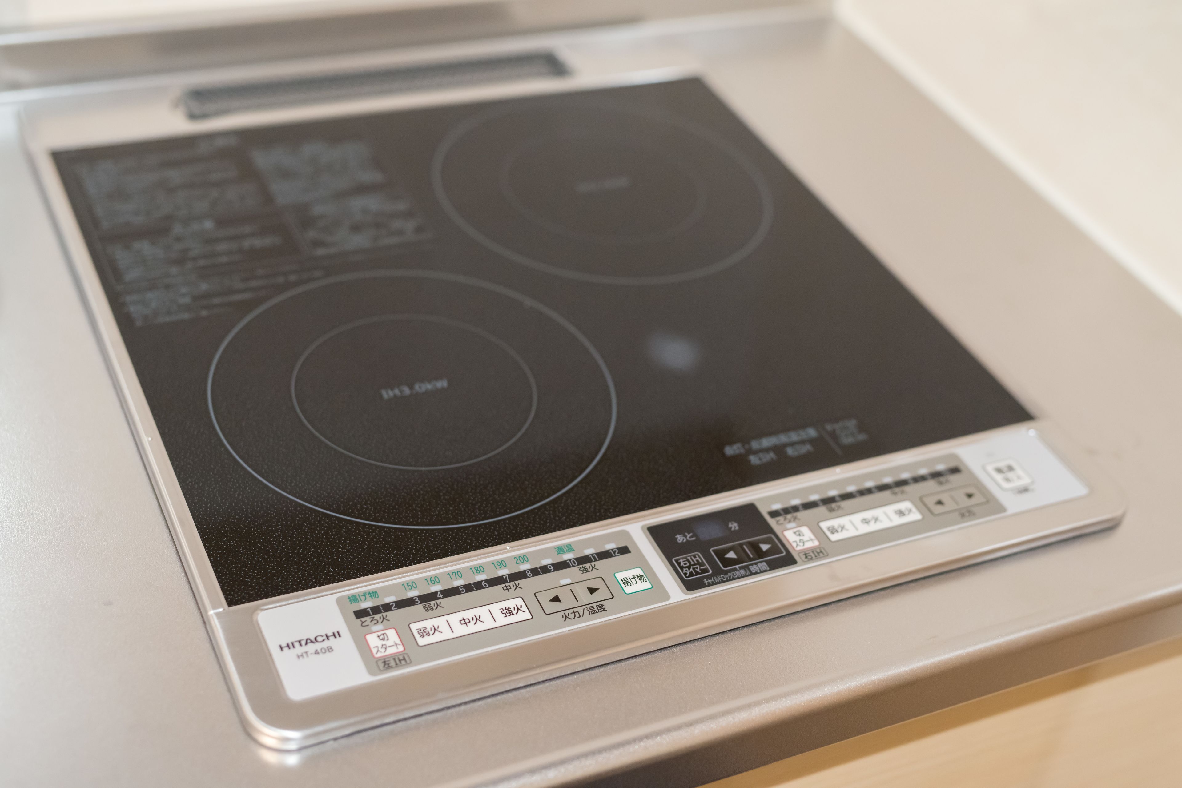 A kitchen with a built-in induction cooktop and a control panel with multiple buttons and settings.