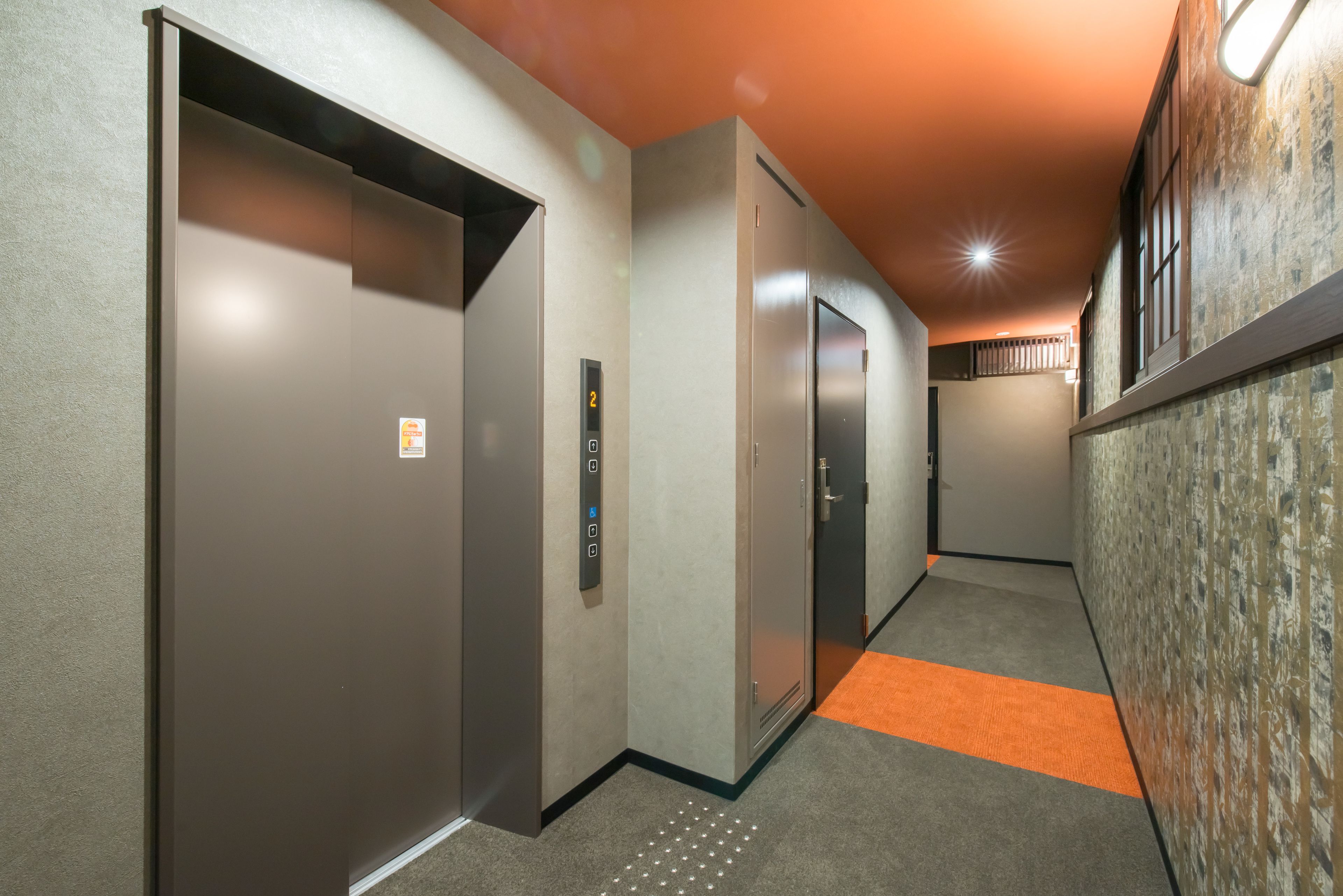 A hallway with three elevators, carpeted floors, and a textured wall on the right.