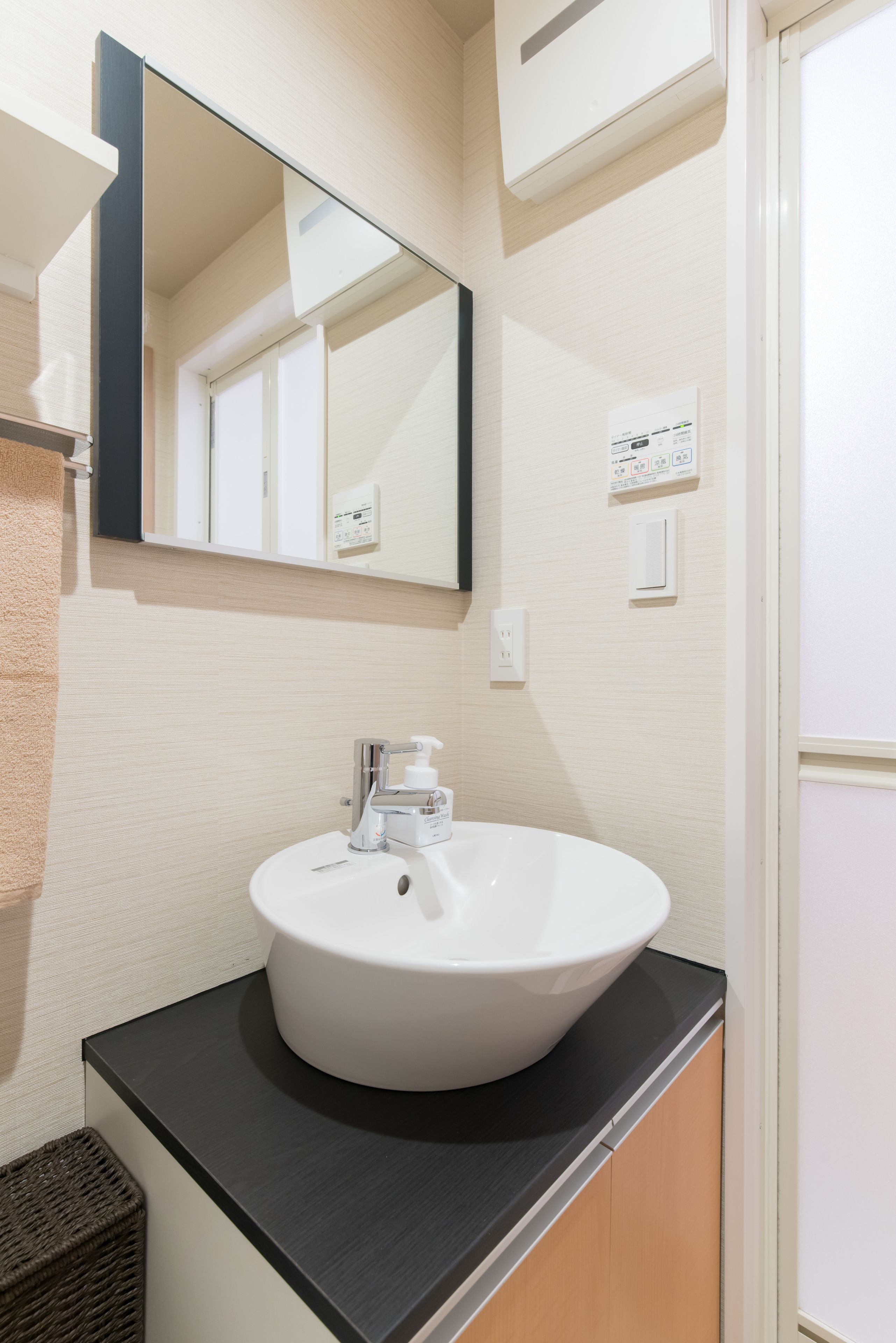 A bathroom with a white sink, a black countertop, a mirror, and a towel rack.