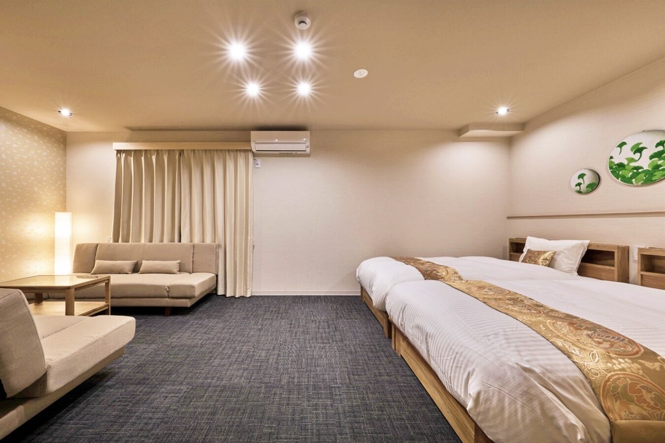Quarto de hotel com cama, sofá, escrivaninha e janela com cortinas.