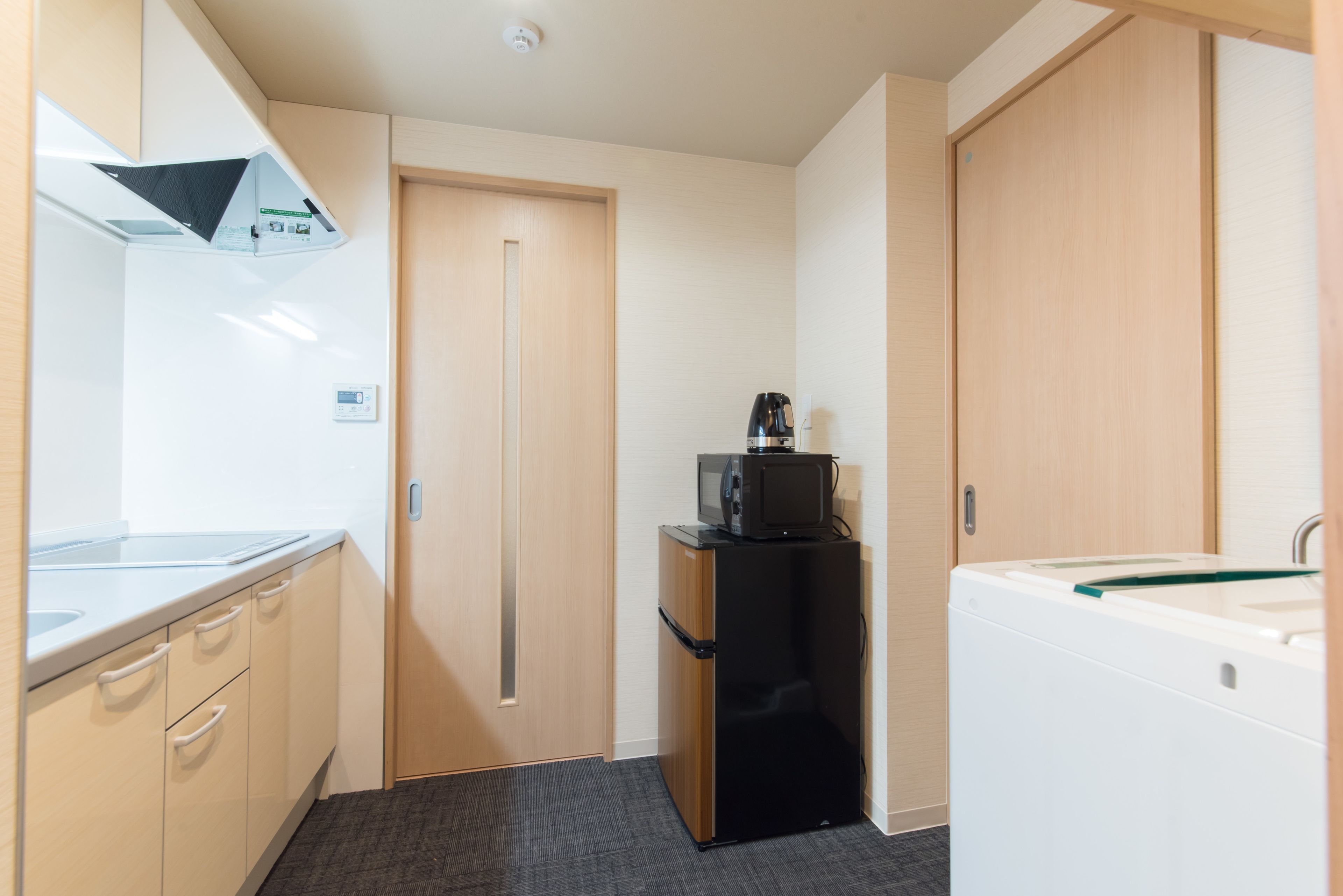 A compact kitchen with a refrigerator, microwave, and washing machine.
