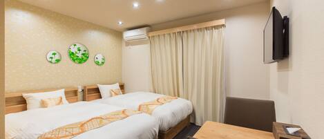 A hotel room with two beds, a wooden desk, a television, and an air conditioning unit.