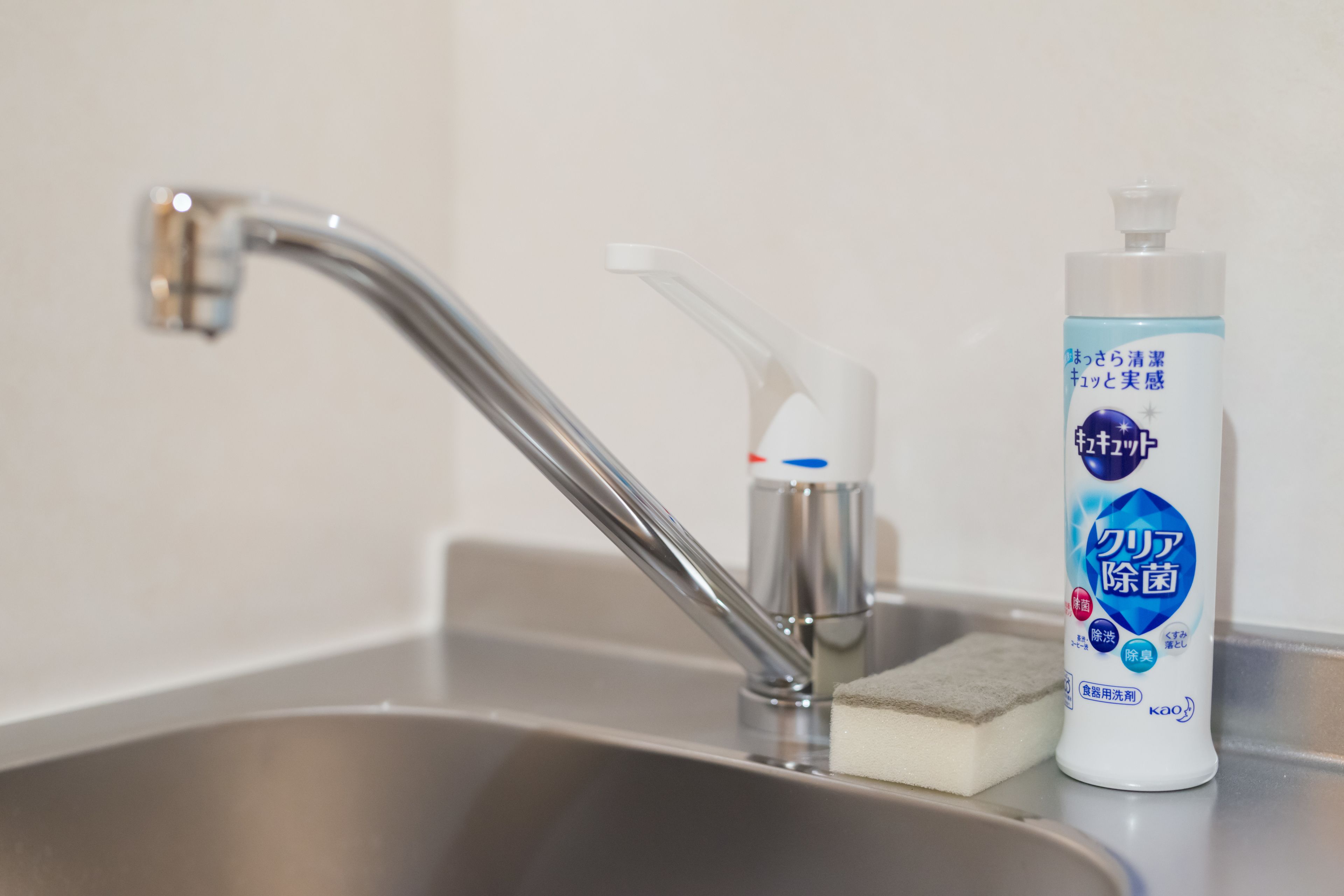 A stainless steel sink with a faucet, a soap dispenser, and a sponge.