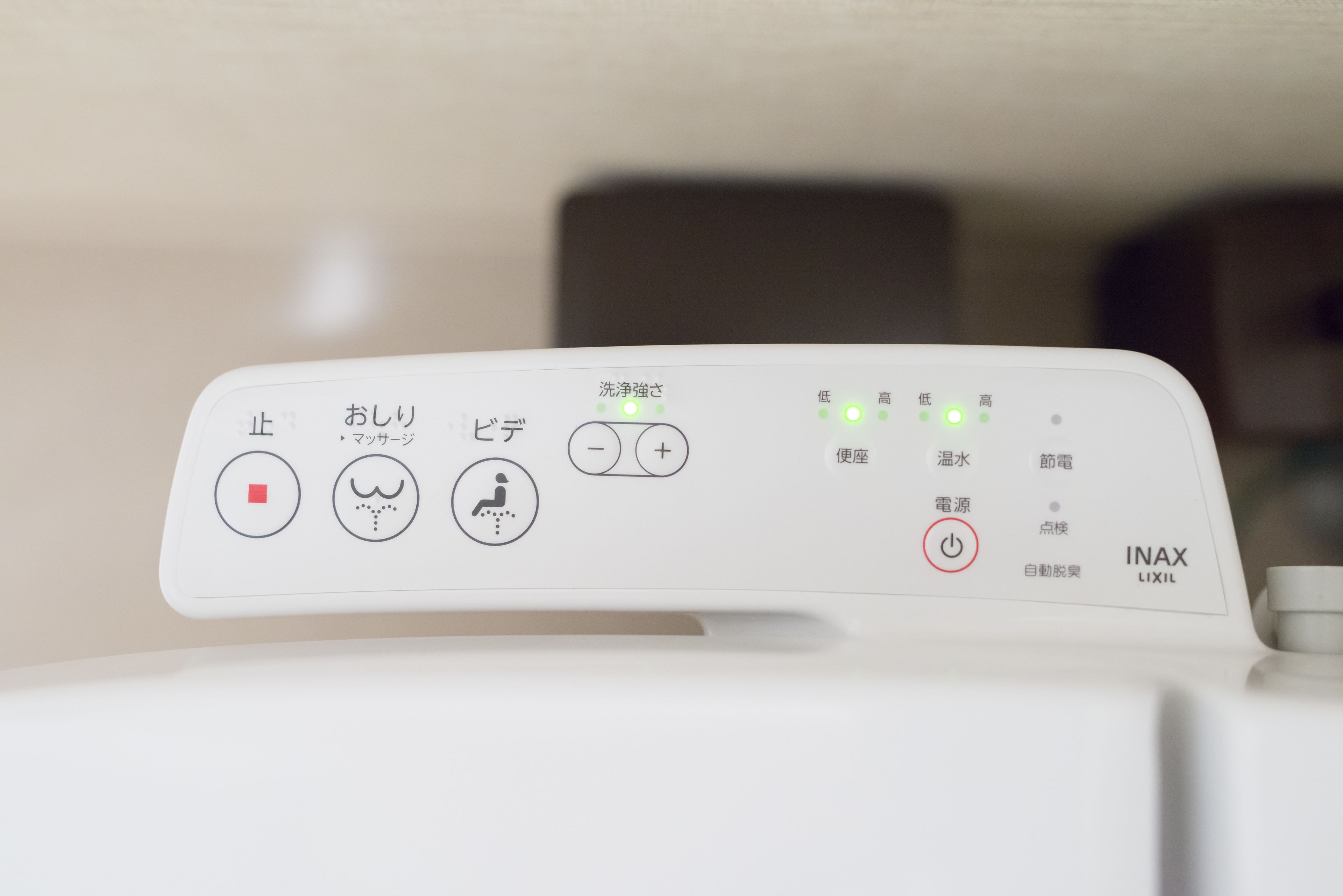 A control panel with various buttons and indicators, including a power button, a button with a red square, a button with a winking face, and a button with a person washing hands.