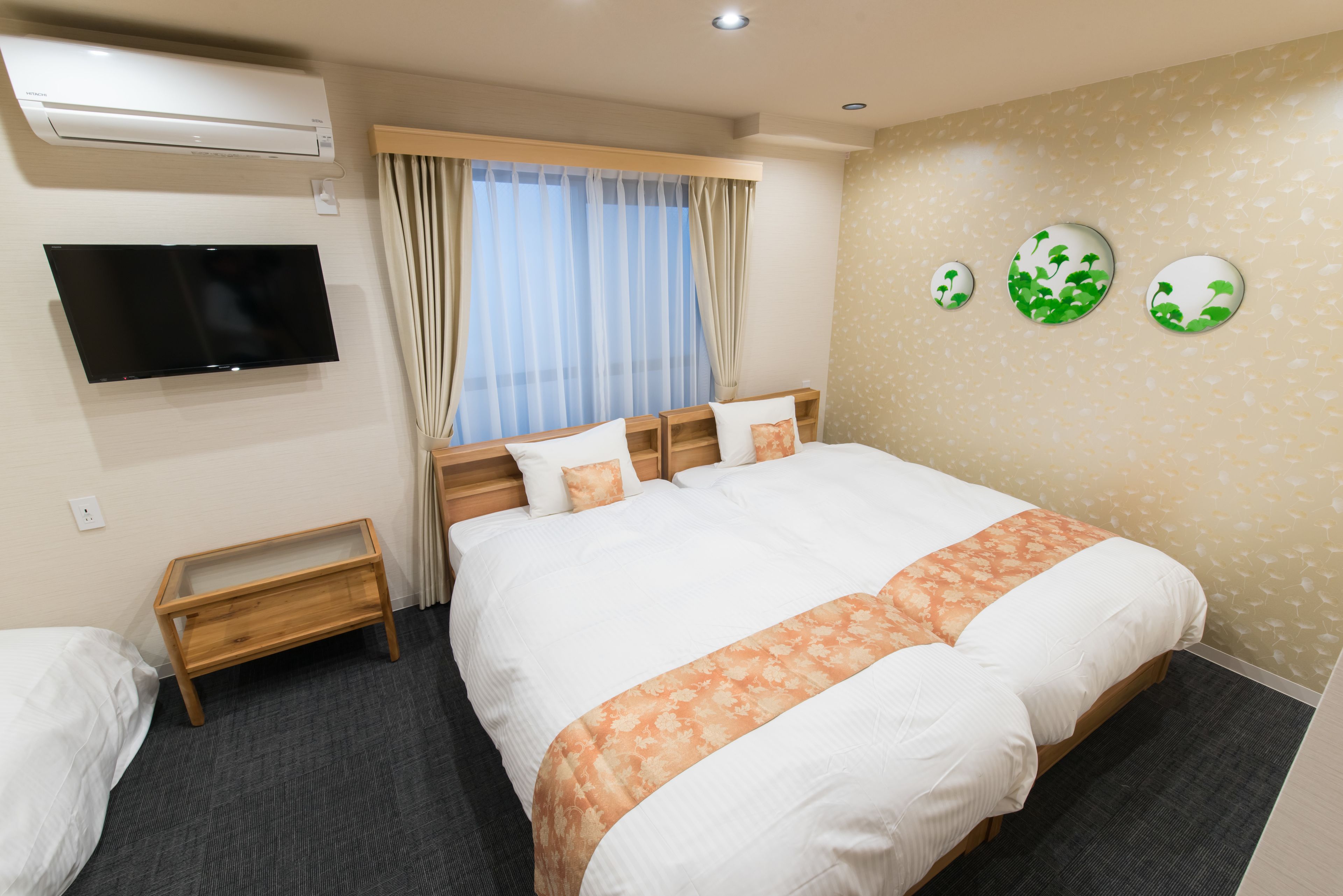 Ein Hotelzimmer mit einem großen Bett, einem Fernseher, einem Nachttisch und einem Fenster mit Vorhängen.