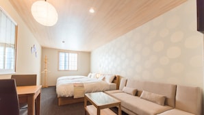 Una habitación de hotel moderna con cama, sofá, escritorio y un amplio ventanal.