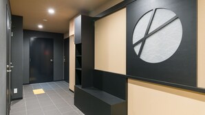 Un pasillo moderno con una paleta de colores negro y beige, que presenta un gran diseño circular en la pared y un suelo de baldosas.