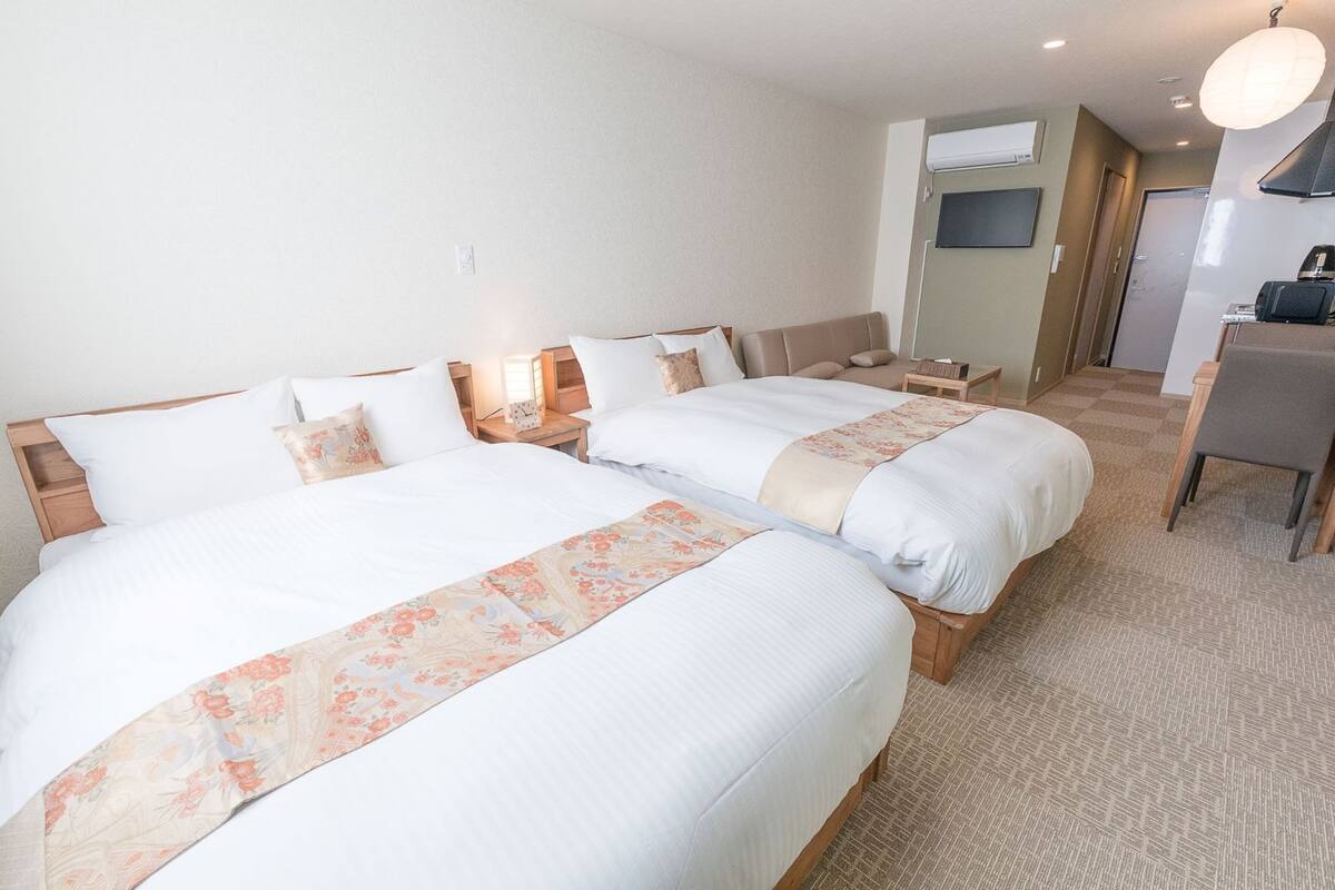 A hotel room with two beds, a small desk, a chair, and a television.