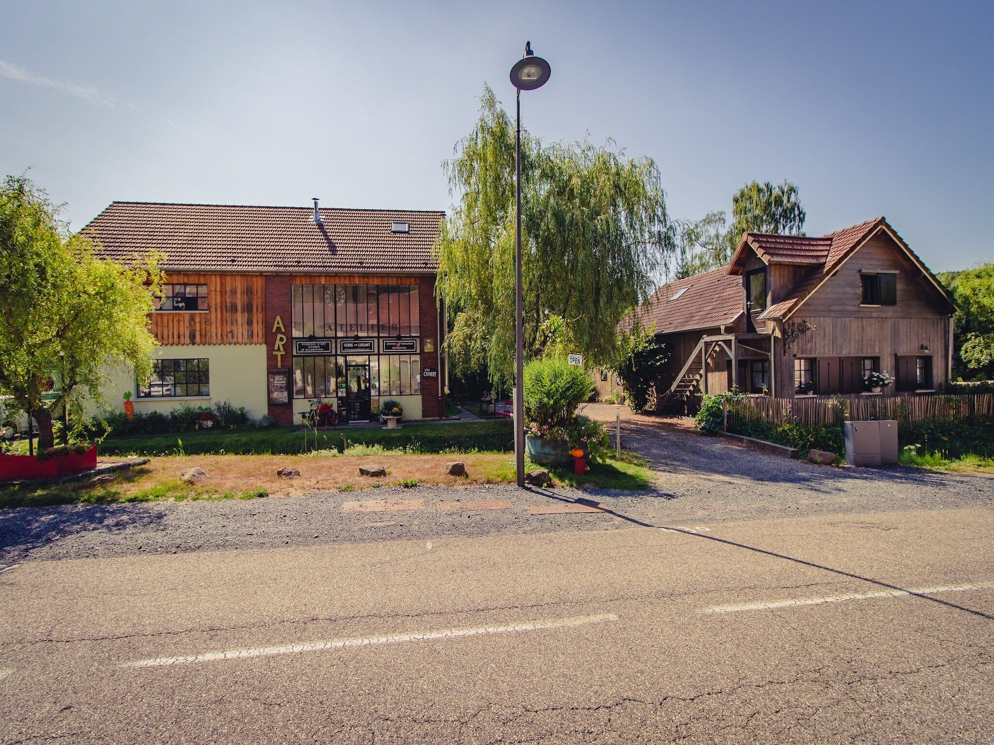 A rustic building with a tiled roof, a wooden facade, and a sign indicating it is an art gallery.