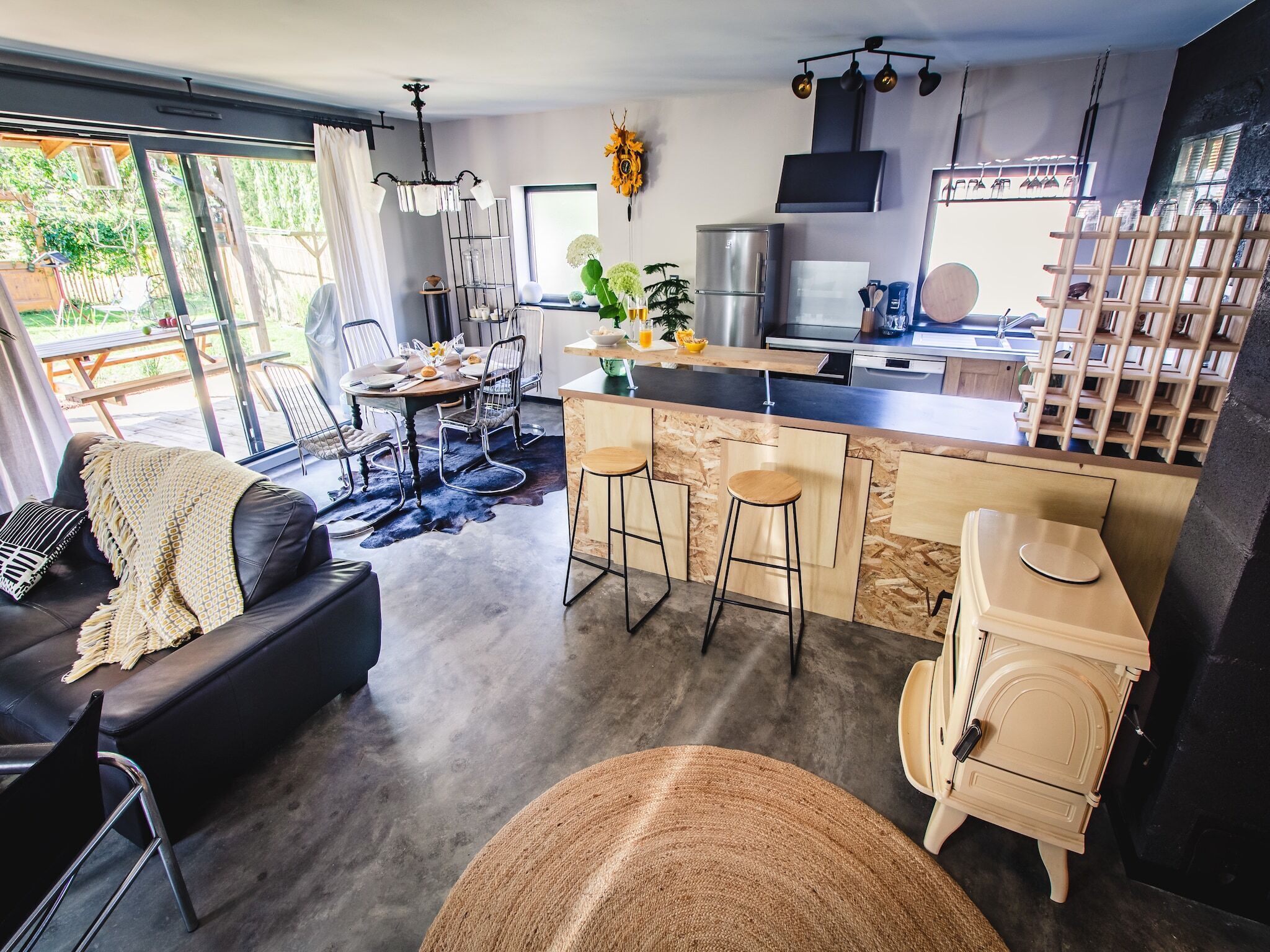 Una cucina moderna con isola centrale, sgabelli da bar e zona pranzo con divano e sedie.