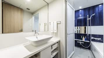 Un baño moderno con un lavamanos blanco grande, un espejo y una zona de ducha con pared de azulejos azules.