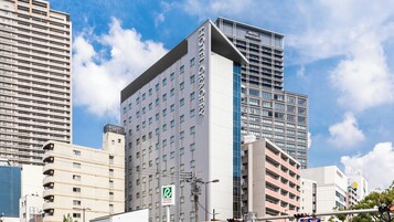 Un hotel moderno con un letrero llamativo, varios pisos y una arquitectura que combina vidrio y concreto.