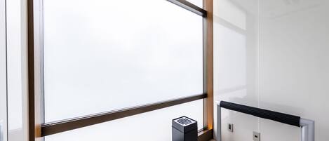A modern elevator with a black control panel, a glass door, and a metal handrail.