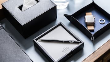 Un bolso de cuero negro, un bolígrafo, un reloj y un anillo sobre una mesa.