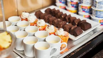 Una presentación de postres que incluye cupcakes con crema batida y brownies, dispuesta en bandejas.