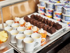 A display of desserts including cupcakes with whipped cream and brownies, arranged on trays.
