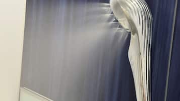 A bathroom with a modern, curved showerhead mounted on a wall.