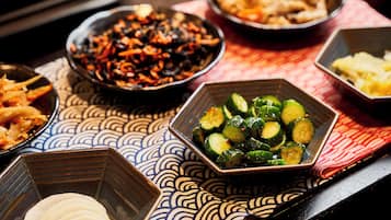 A table with various dishes, including a bowl of sliced cucumbers and a bowl of what appears to be a vegetable stir-fry.
