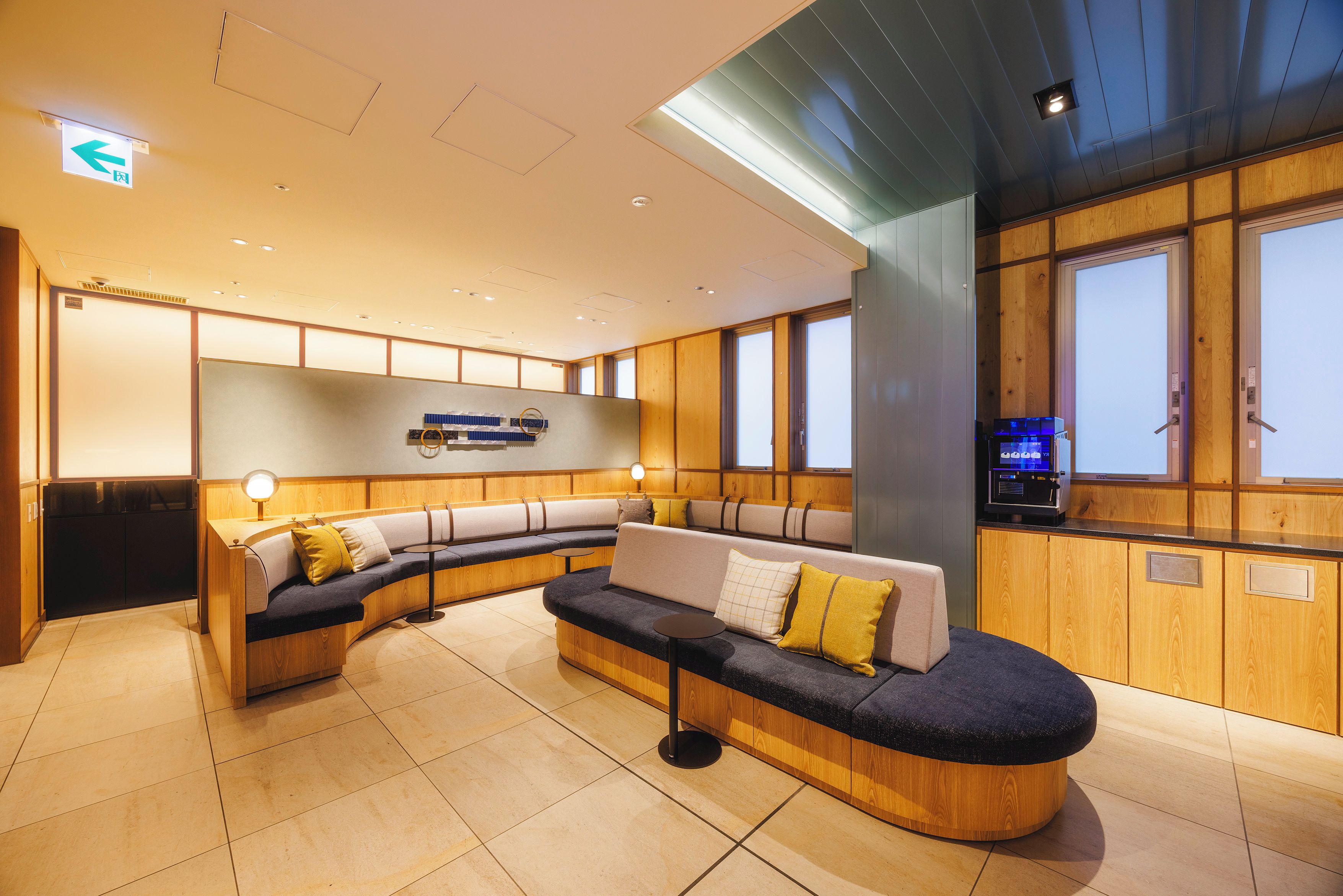 A modern waiting area with a curved seating arrangement, a reception desk, and a large digital display.
