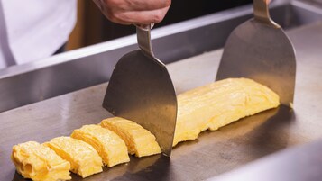 Una persona cortando un bloque grande de comida amarilla sobre una superficie de metal.