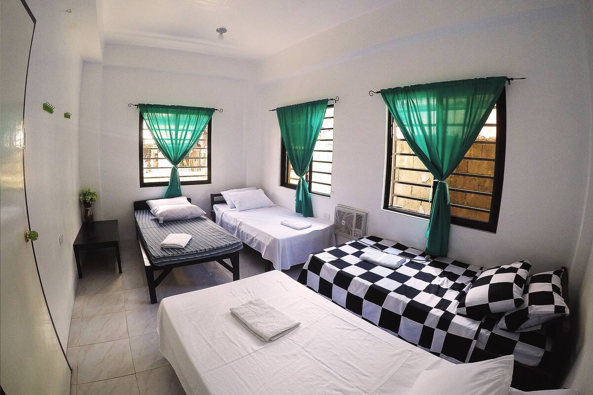 Una habitación con dos camas, una mesita y una silla.