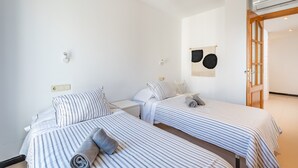 Ein Hotelzimmer mit zwei Einzelbetten, einem kleinen Tisch und einer Wand-Klimaanlage.