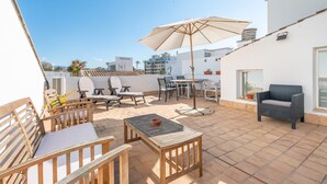 Eine Terrasse mit Gartenmöbeln, einem Tisch und einem großen Sonnenschirm.
