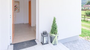 A modern entrance with a door leading to a hallway, a small potted plant, and a lantern on the porch.