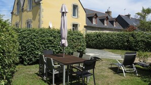 A yellow house with a garden patio featuring a table and chairs. - Holiday house near the beaches (Penmarch)