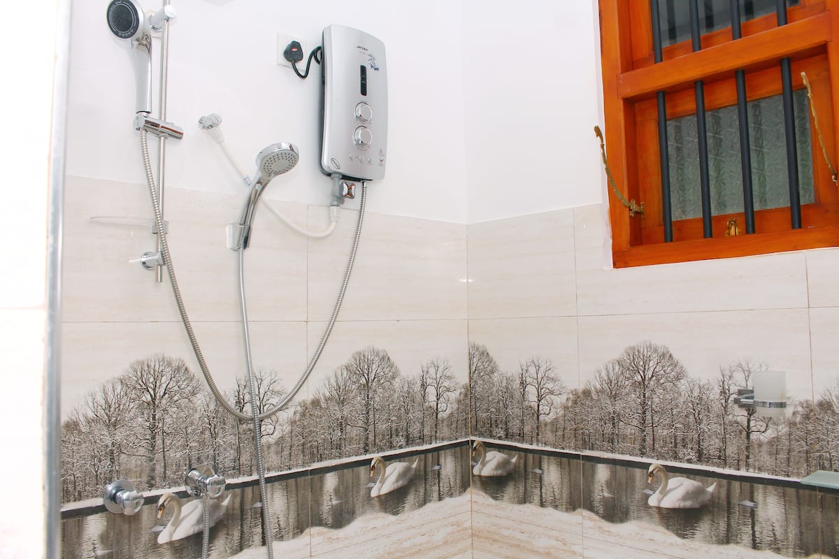 A bathroom with a shower system, a wall-mounted telephone, and a window with a wooden frame.