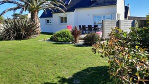 A house with a sloped roof, a patio with outdoor furniture, and a well-maintained lawn.