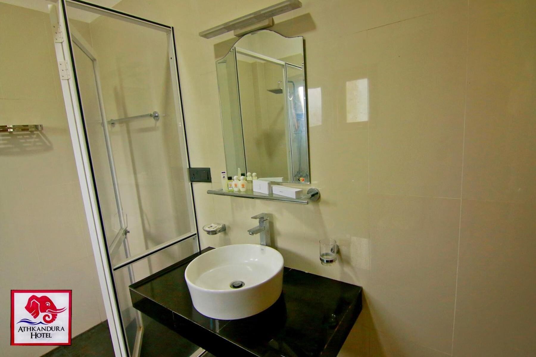A bathroom with a glass shower enclosure, a white sink, and a mirror above it.