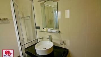 A bathroom with a glass shower enclosure, a white sink, and a mirror above it.