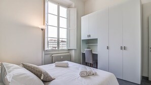 Ett hotellrum med en säng, ett skrivbord och en garderob.