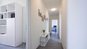 En hall med vita hyllsystem, en vas med blommor och inramade tavlor på väggen.