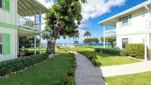 Un resort con un paseo cubierto, exuberante vegetación y vista al océano.