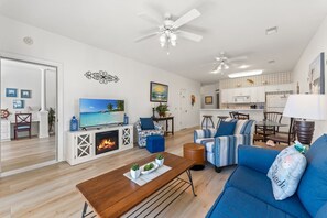 Una sala de estar moderna con chimenea, televisor y comedor, con una cocina al fondo.