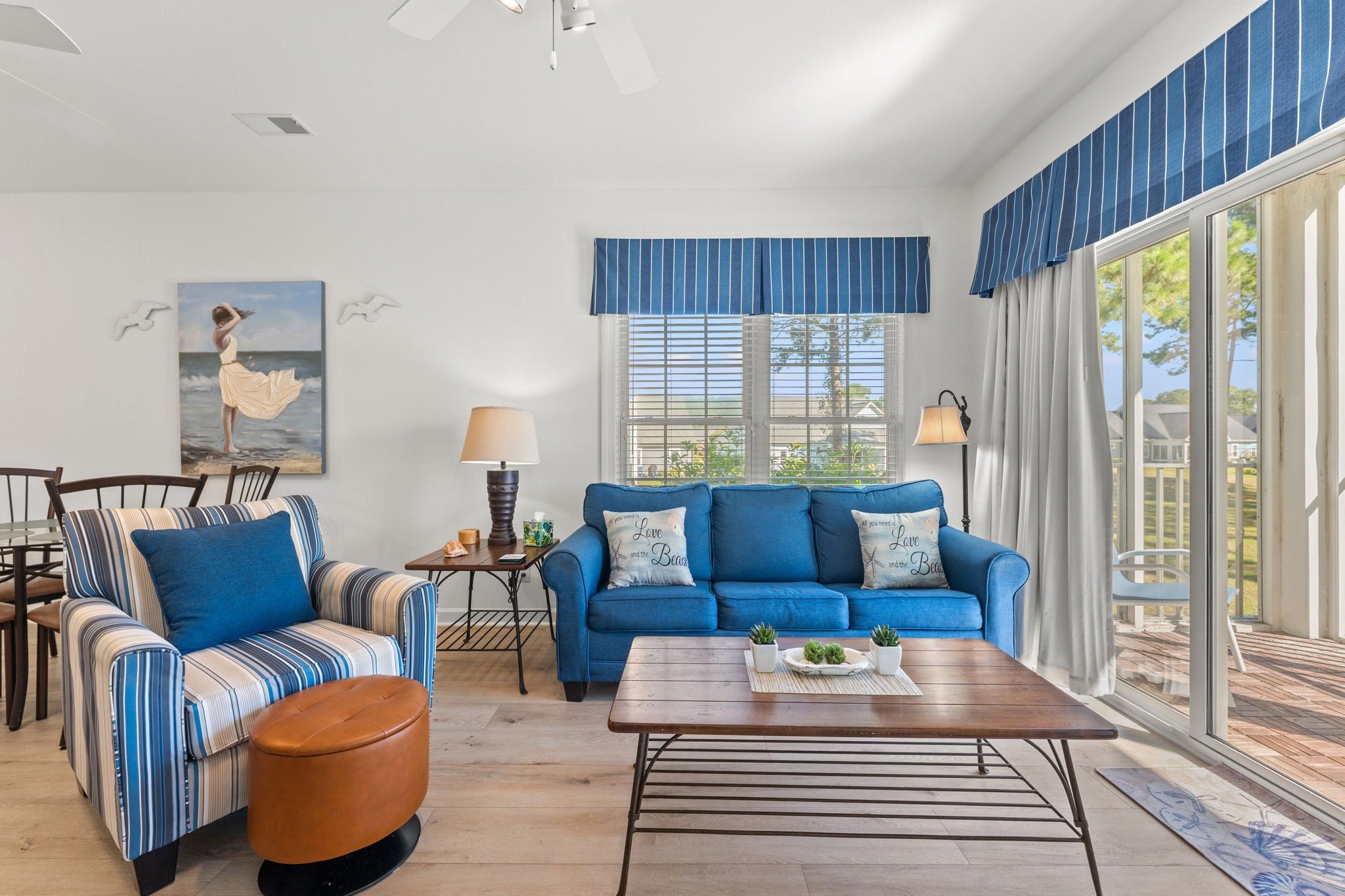 Uma sala de estar moderna com um sofá azul, poltrona listrada e mesa de centro com objetos decorativos.