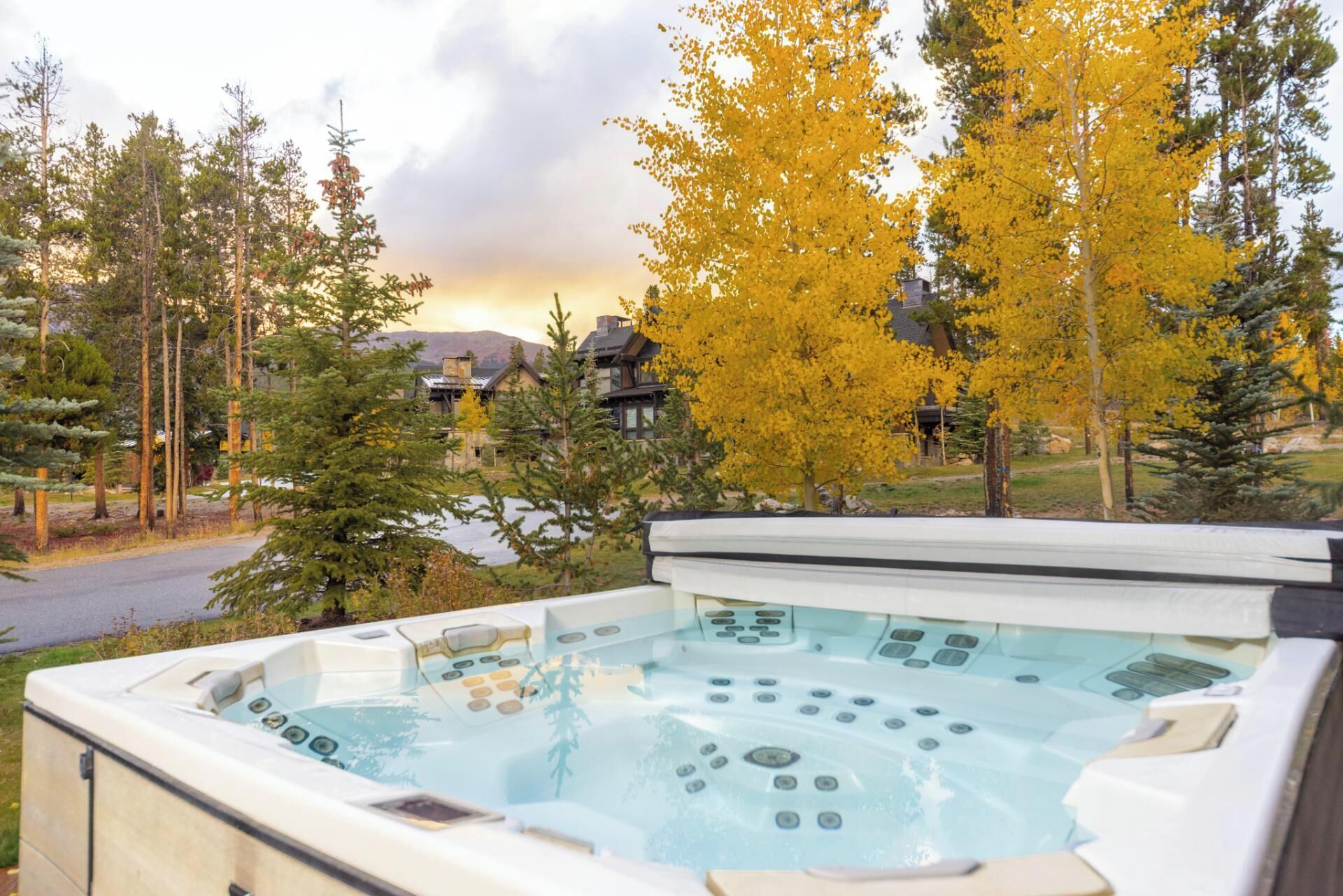 A hot tub with a control panel, surrounded by trees and a view of buildings in the background.