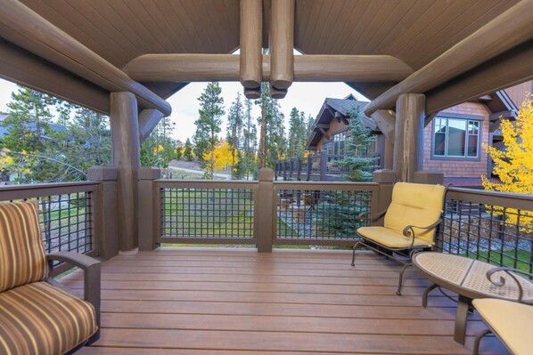 Eine überdachte Terrasse mit Holzboden, Metallgeländern und zwei gelben Stühlen.